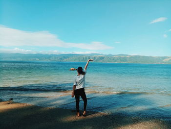 Rear view of man standing at beach against sky