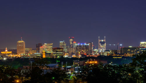 Illuminated buildings in city against sky at night