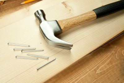 Close-up of hammer with nails on wooden table at carpentry