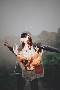 Man standing by burning newspaper