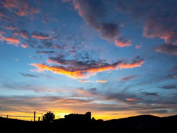 Silhouette trees against dramatic sky during sunset