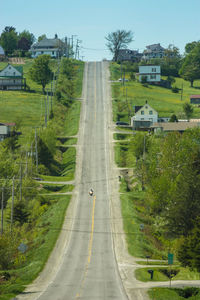 Road amidst trees and houses against clear sky