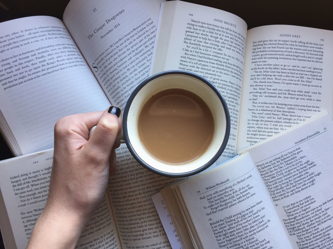 publication, cup, book, coffee cup, mug, coffee, drink, human hand, coffee - drink, one person, holding, paper, hand, refreshment, human body part, food and drink, real people, indoors, high angle view, text, studying, finger, crockery