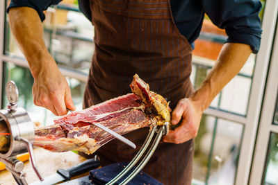 Midsection of man cutting meat