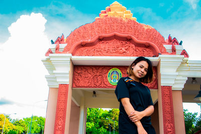 Low angle portrait of young woman standing against castle