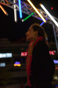 Side view of woman looking at illuminated stage