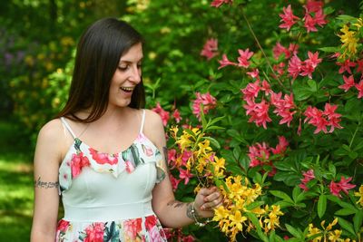 Smiling young woman standing flowers in garden
