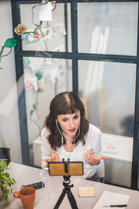 High angle view of businesswoman attending video conference through mobile phone at desk in office