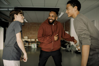 Smiling male dance teacher teaching teenage students in studio at high school