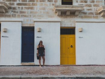 Portrait of woman standing against door of building