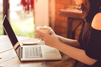 Close-up of woman holding coffee cup on table at cafe