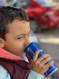 Portrait of young boy drinking a can of cola