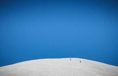 Low angle view of snowcapped mountain against clear blue sky