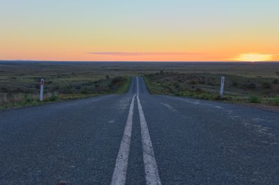 Road passing through landscape during sunset