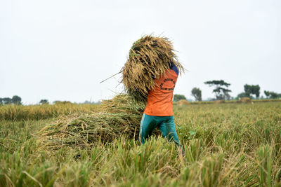 Rear view of woman standing on field against clear sky