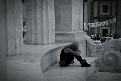 Full length of woman sitting on steps in city