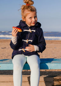 Girl in delight eats donut with red icing, food stained her mouth