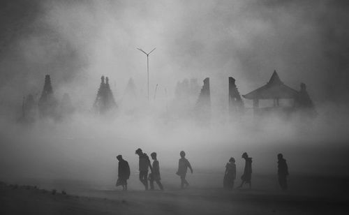 Silhouette children and buildings in foggy weather