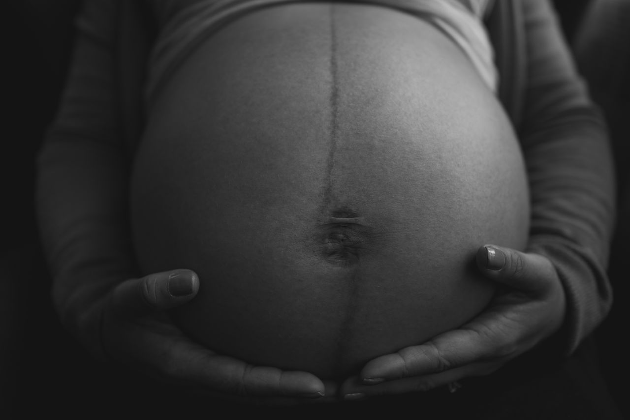 MIDSECTION OF WOMAN WITH BABY HAND ON FACE