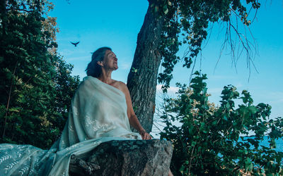 Woman standing by tree against plants