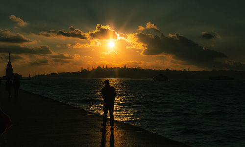 Silhouette of a man  next to the  sea during sunset