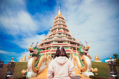 Rear view of woman standing outside temple against building