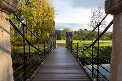 Footbridge amidst trees against sky