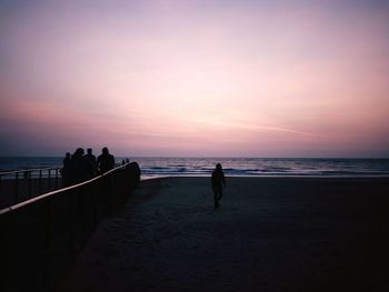 Silhouette people on beach against sky during sunset