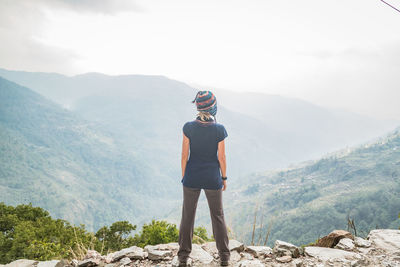 Rear view of woman standing on mountain against sky