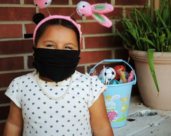 Portrait of cute girl holding potted plant at home