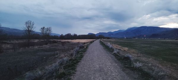 Empty road along landscape and mountains against sky