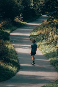 Full length rear view of man walking on road