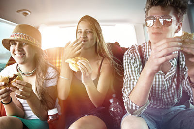 Three teenage friends having a snack in car