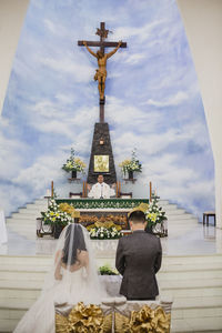 Rear view of bride and groom standing at altar during wedding ceremony
