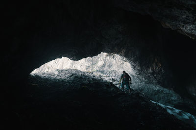 Silhouette man climbing on rock in cave