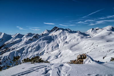 Scenic view of snow covered mountains against blue sky