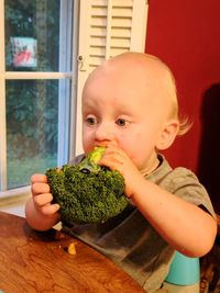 Portrait of boy eating broccoli at home