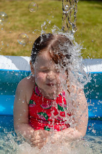 Close-up of playful girl splashing water in wading pool