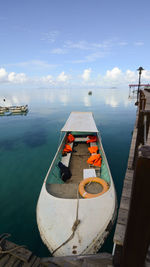 Boats moored at harbor against sky