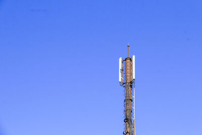 Low angle view of communications tower against blue sky