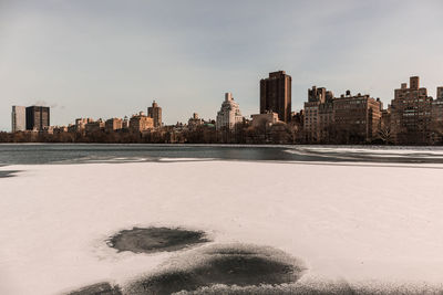 Scenic view of beach by city against sky during winter