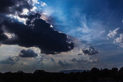 Low angle view of silhouette trees against dramatic sky