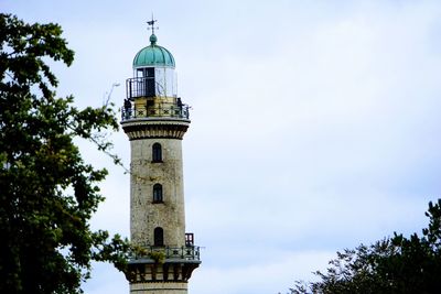 Low angle view of lighthouse by building against sky