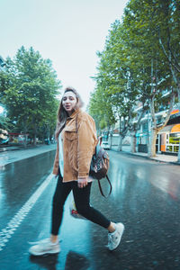 Young woman smiling while standing on road in city