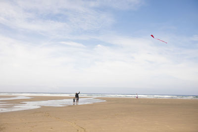 Father teaching son how to fly a kite at the beach.