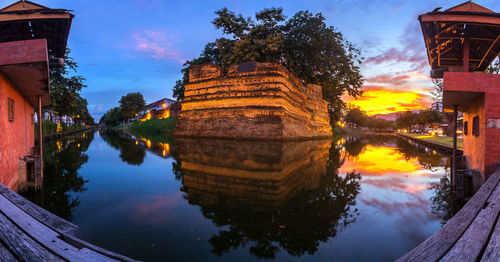 Reflection of buildings and trees in lake against sky