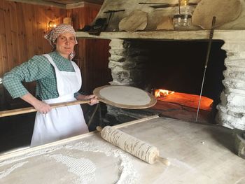 Portrait of woman making pizza at commercial kitchen