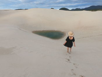 Rear view of woman walking on sand at desert