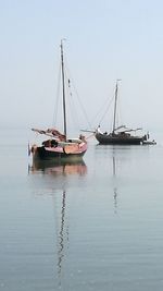 Boats sailing in sea against clear sky