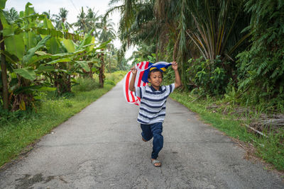 Full length of boy with malaysian flag running on road